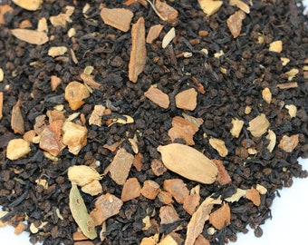 May include: A close-up of a blend of black tea leaves, cinnamon sticks, ginger, and other spices. The tea is a dark brown colour and the spices are a light brown colour.