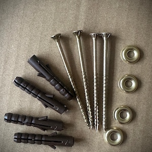 May include: A selection of hardware components, including brown plastic wall plugs, gold-coloured screws, and metal washers. The items are arranged on a neutral-toned surface, suitable for DIY projects.