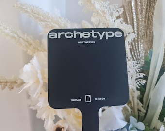 Puede incluir: Señal cuadrada negra con texto blanco que dice "archetype aesthetics" y "the place" y "to med spa".
