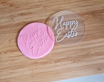 May include: A clear acrylic stamp with the text "Happy Easter" in white lettering. The stamp is on top of a pink silicone stamp with the same text.