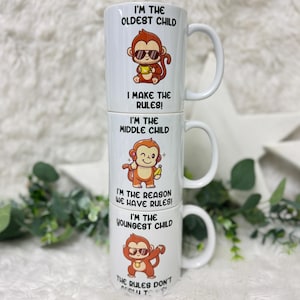 May include: A white ceramic mug with a stack of four different designs featuring a cartoon monkey with the text "I'm the oldest child I make the rules! I'm the middle child I'm the reason we have rules! I'm the youngest child The rules don't apply to me!"