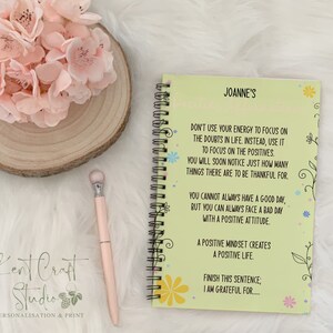 May include: A green and yellow notebook with a floral design and the text "Joanne's" and "Don't use your energy to focus on the doubts in life. Instead, use it to focus on the positives. You will soon notice just how many things there are to be thankful for."  The notebook also has the text "You cannot always have a good day, but you can always face a bad day with a positive attitude."  The notebook also has the text "A positive mindset creates a positive life."  The notebook also has the text "Finish this sentence; I am grateful for..."