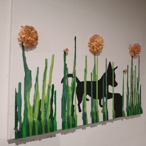May include: A black silhouette of a dog running through a field of green grass with three orange flowers on top.
