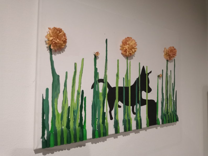 May include: A black silhouette of a dog running through a field of green grass with three orange flowers on top.