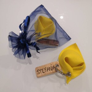 K&ouml;nnte beinhalten: Zwei gelbe Gl&uuml;ckskeks-Schl&uuml;sselanh&auml;nger aus Stoff mit Holzetiketten. Ein Etikett lautet "Stefania" und das andere "Capri, Italien".