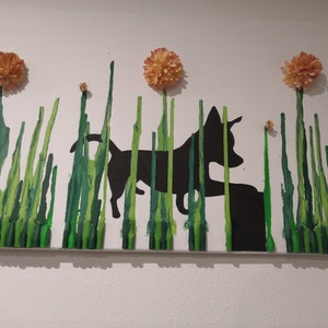 May include: A black silhouette of a dog walking through a field of green grass with orange flowers. The grass is made of melted crayons.