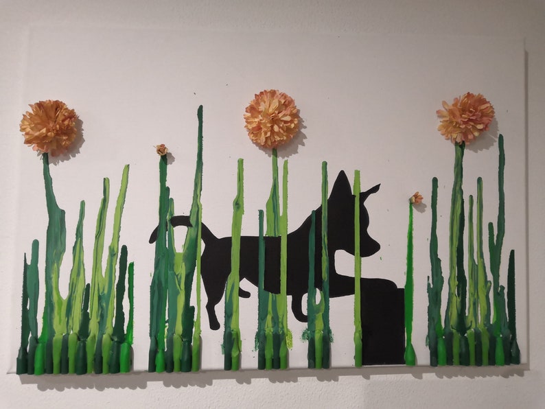 May include: A black silhouette of a dog walking through a field of green crayon art. The dog is walking towards a small flower. There are three orange flowers at the top of the art piece.