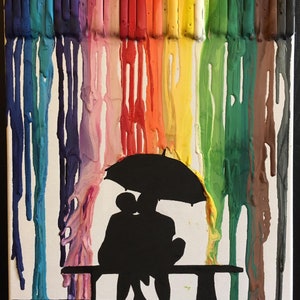 May include: A colorful abstract painting of melted crayons on a white canvas. The melted crayons create a rainbow effect. A silhouette of two people sitting on a bench under an umbrella is in the foreground.