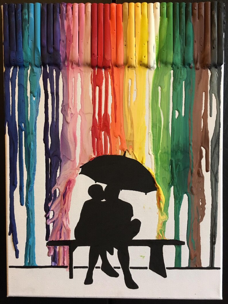 May include: A colorful abstract painting of melted crayons on a white canvas. The melted crayons create a rainbow effect. A silhouette of two people sitting on a bench under an umbrella is in the foreground.