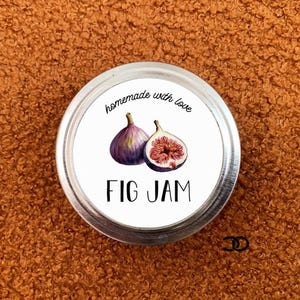 Peut inclure: Une étiquette ronde blanche pour pot avec une illustration en noir et blanc de deux figues. L'étiquette indique "homemade with love" et "FIG JAM".