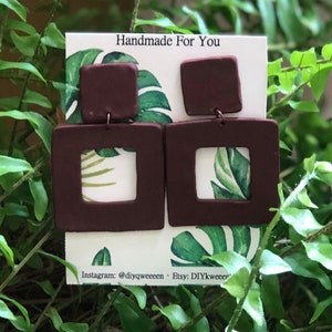 May include: Burgundy square earrings with a smaller square top and a larger square with a cutout. The earrings are displayed on a card with a tropical leaf design and the text "Handmade For You". Instagram and Etsy information is also visible.
