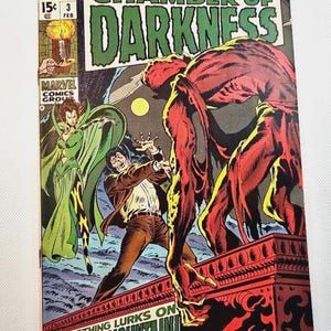 Może przedstawiać: Komiks w stylu vintage zatytułowany "Chamber of Darkness" z dramatyczną ilustracją. Okładka przedstawia czerwonego potwora atakującego mężczyznę, kobietę w zieleni i tekst "Something Lurks on Shadow Mountain!"