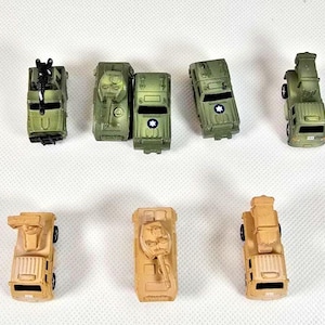 Puede incluir: Una colección de vehículos militares de juguete en miniatura en tonos verdes y beige. El surtido incluye tanques, camiones y otros vehículos de estilo militar. Los juguetes están dispuestos sobre una superficie blanca.
