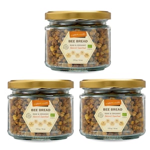 Może przedstawiać: Trzy szklane słoiki ze złotymi pokrywkami wypełnione chlebem pszczelim. Każdy słoik ma białą etykietę z tekstem "earth breath BEE BREAD RAW & ORGANIC Nature's Superfood" i listą witamin i minerałów. Słoiki mają pojemność 170g/6oz.