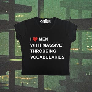 May include: Black crop top with the text "I ❤️ MEN WITH MASSIVE THROBBING VOCABULARIES" in white and red. The shirt has a crew neck and short sleeves. The top is made of a soft material.