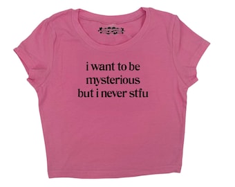 Puede incluir: Camiseta rosa de manga corta y corte corto con el texto "i want to be mysterious but i never stfu" impreso en negro.