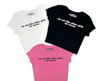 May include: Three cropped t-shirts with the text "im not like other girls, im worse" in black lettering. The shirts are white, black, and pink.