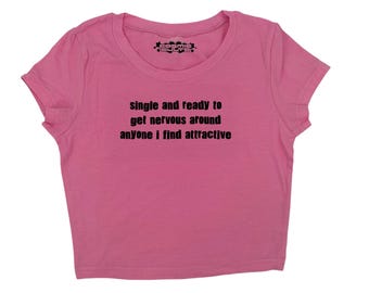 May include: Pink cropped t-shirt with the text "single and ready to get nervous around anyone i find attractive" printed in black.