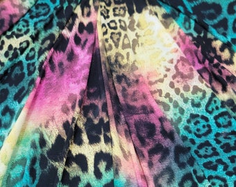 May include: Close-up of a fabric with a colorful ombre pattern and a leopard print. The fabric is a blend of turquoise, pink, yellow, and brown.