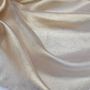 May include: A close-up of a piece of gold fabric with a subtle shimmer. The fabric has a slightly textured surface and a fringed edge.