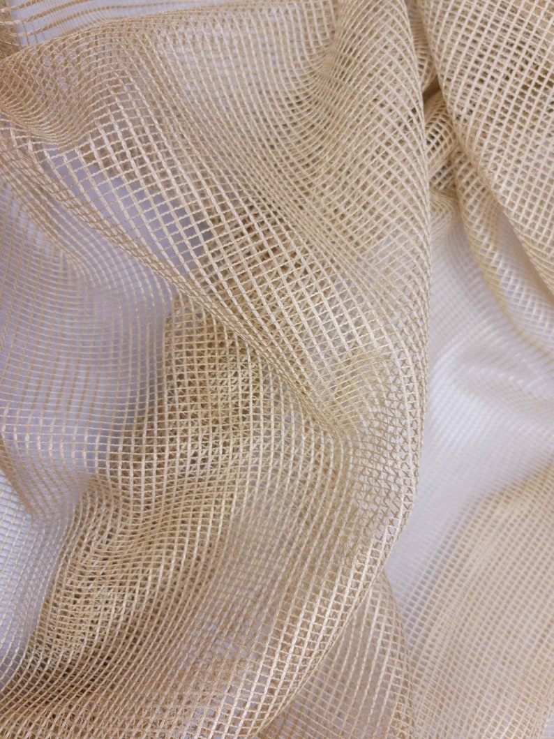 May include: A close-up of a beige mesh fabric with a woven pattern. The fabric is soft and has a delicate texture.