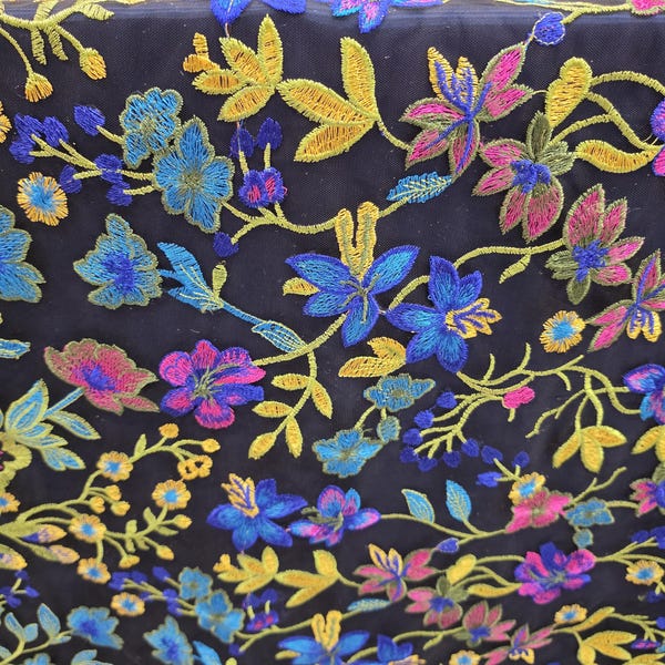 Tela vendida cortada a medida. Encaje multicolor bordado con flores rosas, amarillas y azules sobre malla negra.