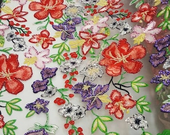 Puede incluir: Una tela de malla blanca con flores bordadas de colores. Las flores son rojas, rosas, moradas, amarillas y verdes. La tela está adornada con lentejuelas y cuentas.