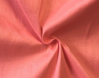 Könnte beinhalten: Nahaufnahme eines korallenfarbenen Stoffes mit dezentem Glanz. Das Material ist in weichen Falten gelegt, wodurch Schatten und Lichteffekte entstehen. Der Stoff wirkt glatt und leicht, geeignet für Kleidung oder Dekorationsprojekte.