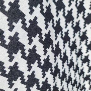 May include: Black and white houndstooth fabric with a textured surface.