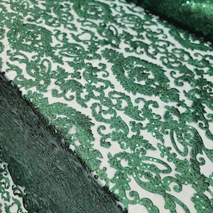 以下が含まれることがあります： エメラルドグリーンのビーズ付きレース生地で、ダマスク柄です。生地は柔らかく繊細で、ビーズは均等に配置されています。