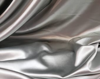 May include: Close-up of a smooth, silver satin fabric with soft folds and wrinkles.