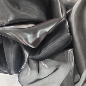 May include: Black sheer fabric with a shiny, iridescent finish. The fabric is draped and folded, showcasing its texture and drape.