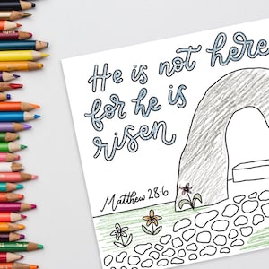 May include: A coloring page with the text "He is not here for he is risen" and "Matthew 28:6". The image depicts an empty tomb with a path and flowers. A set of colored pencils is on the left.