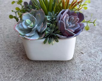 Faux succulent arrangement in white ceramic container