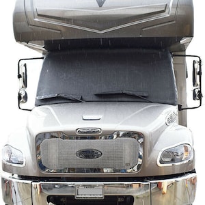May include: A silver and gray recreational vehicle with the word "Valencia" on the front. The vehicle has a chrome grill and bumper, with the Freightliner logo visible. The windshield wipers are in place.