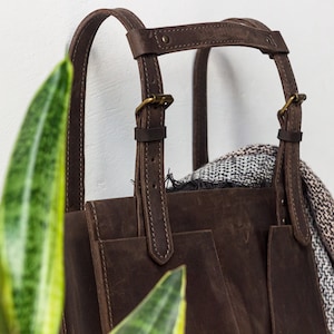 A close up of the brown leather tote adjustable handle with the unique design.