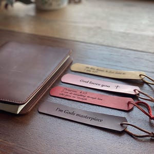 Könnte beinhalten: Vier Leder-Lesezeichen mit verschiedenen inspirierenden Botschaften. Die Lesezeichen sind braun, rosa und rot. Die Botschaften lauten: "Ich bin Gottes Meisterwerk", "Philipper 4:13 Ich kann alles durch ihn, der mir Kraft gibt", "Gott liebt dich" und "Mein Glaube hat mich so weit gebracht und ich glaube, dass Gott mich den Rest des Weges führen wird".