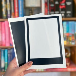 May include: Two rectangular magnetic sheets with a white center and a thick black border. The magnets have a vertical orientation and a smooth finish, designed to frame items or serve as a blank display surface for notes or photos on metal.
