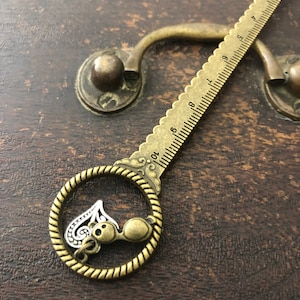 Circle top antique gold pd ruler with hanging glasses and heart charms
