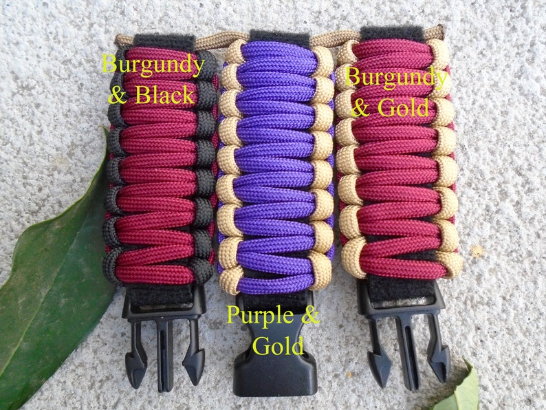 May include: Three paracord bracelets with black clasps. The bracelets are made with burgundy and black paracord, purple and gold paracord, and burgundy and gold paracord. The text "Burgundy & Black", "Purple & Gold", and "Burgundy & Gold" is written on the bracelets.