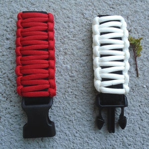 May include: Two paracord bracelets with black buckles. One bracelet is red and the other is white.