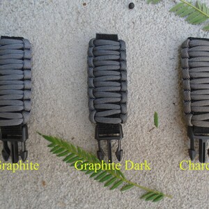 May include: Three grey paracord straps with black buckles. The straps are labelled "Graphite", "Graphite Dark", and "Charcoal".