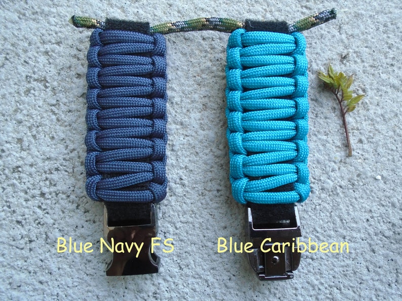 May include: Two paracord keychains, one in navy blue and one in turquoise blue, with black metal clasps. The text "Blue Navy FS" is below the navy blue keychain and "Blue Caribbean" is below the turquoise blue keychain.