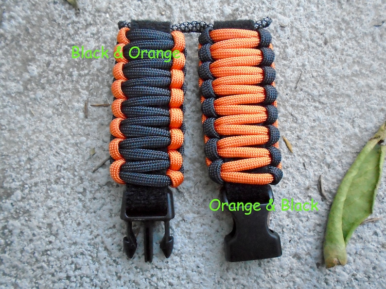 May include: Two paracord bracelets with black and orange woven patterns. The bracelets have black plastic buckles.