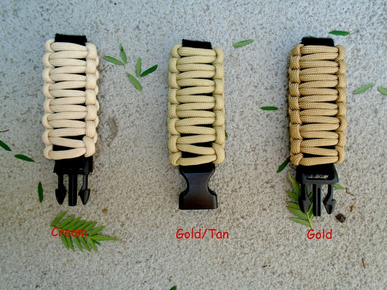 May include: Three paracord bracelets in cream, gold/tan, and gold colours. Each bracelet has a black plastic buckle.