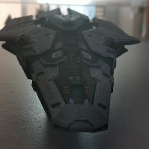 Puede incluir: Un modelo de nave espacial gris oscuro con detalles intrincados y acentos naranjas. El modelo est&aacute; hecho de pl&aacute;stico y tiene un dise&ntilde;o elegante y futurista.