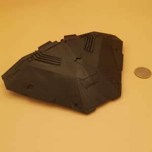 Puede incluir: Un modelo de nave espacial impreso en 3D de color negro con un dise&ntilde;o geom&eacute;trico. El modelo tiene una forma afilada y angular y presenta detalles intrincados.