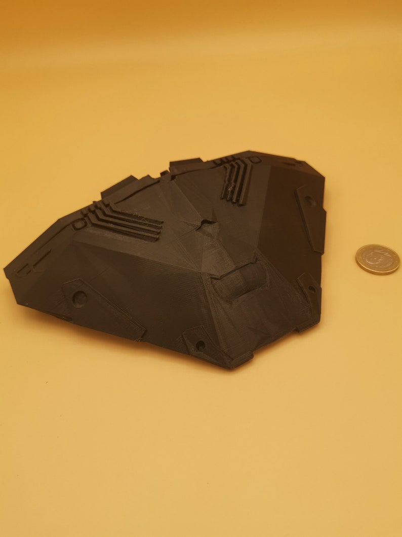 Puede incluir: Un modelo de nave espacial impreso en 3D de color negro con un dise&ntilde;o geom&eacute;trico. El modelo tiene una forma afilada y angular y presenta detalles intrincados.