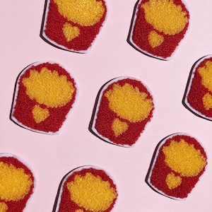 May include: Nine red and yellow felt flower patches with white outlines. The flowers are arranged in a staggered pattern on a pink background.