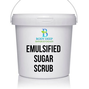 May include: White plastic bucket with a handle, containing a white sugar scrub. The bucket has a green leaf logo with the text "Body Deep Bath|Body|Health" and the text "Emulsified Sugar Scrub".
